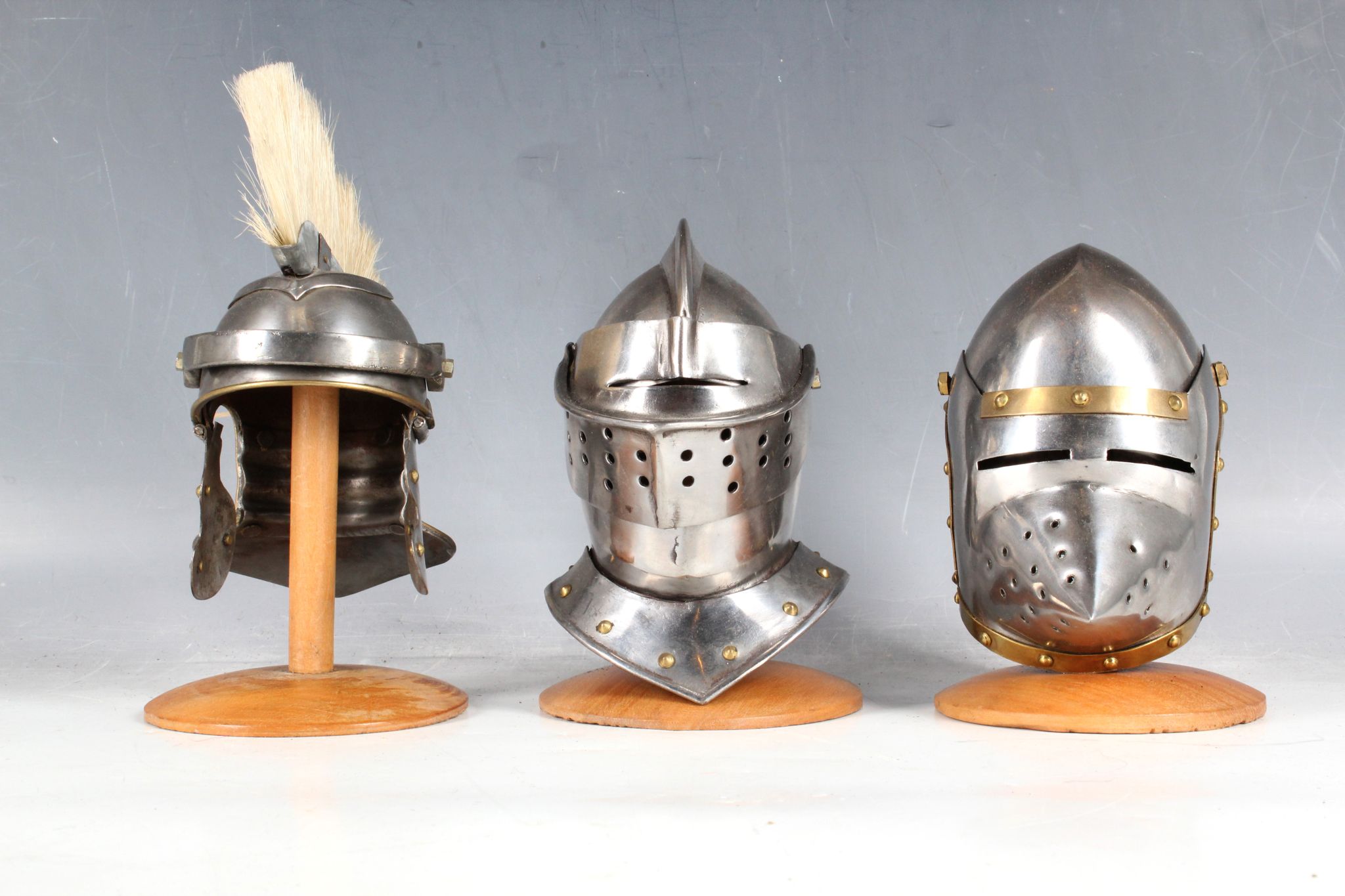 Three miniature desk top helmet ornaments; plumed Roman helmet and two knights visor helmets and