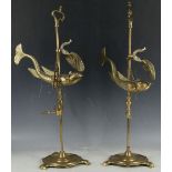 A pair of brass oil lamps, in the form of fish on a stand, raised on a socle base. (2)