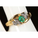 A 20ct (.850 mark) gold, emerald and diamond cross-over ring.