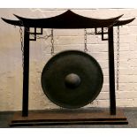 A Chinese influence gong and stand in the form of a temple roof, patinated gong, approx. 52cm