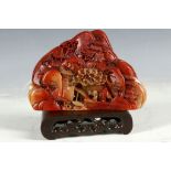 A Chinese Shoushon stone, landscape carving with houses and figures with hardwood stand, 14.2cm w.