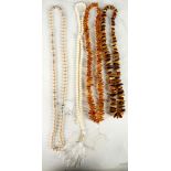 Four mixed necklaces to include: two amber, a white coral and a simulated pearl necklace. (4)