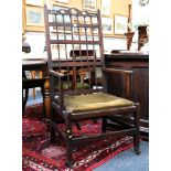 An oak open armchair with carved and pierced top rail over a spindle back over an upholstered,
