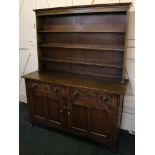 An oak kitchen dresser, with plate rack above frieze drawers, and panelled cupboard doors.