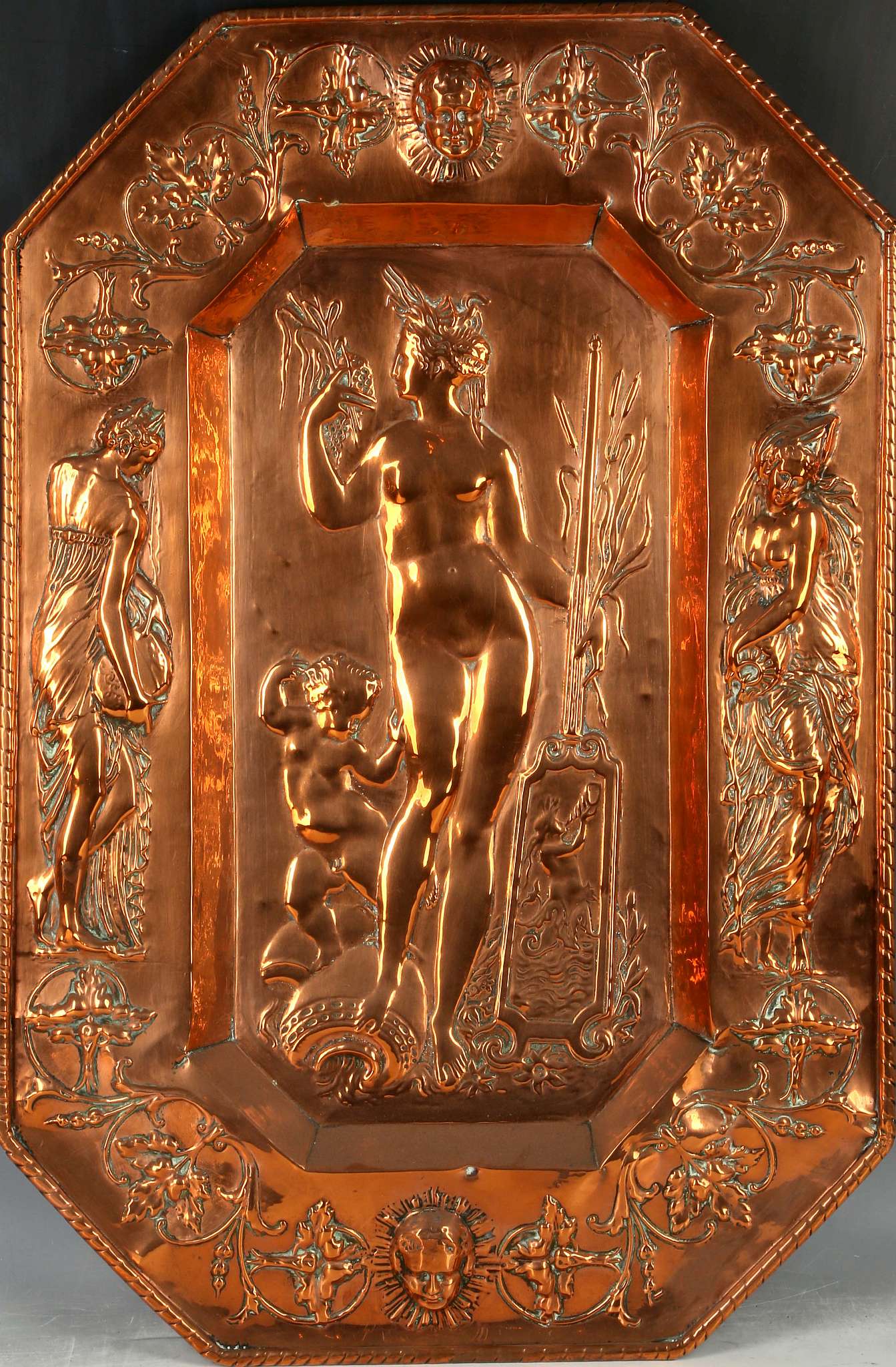 An octagonal repoussé copper dish with classical maiden, possibly Venus, surrounded by maidens.