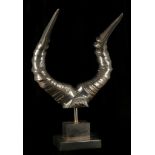 A pair of modern silvered bronze rams horns on steel block base, (44cm high).