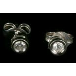 A pair of white gold, diamond stud earrings with silver butterfly clasps.