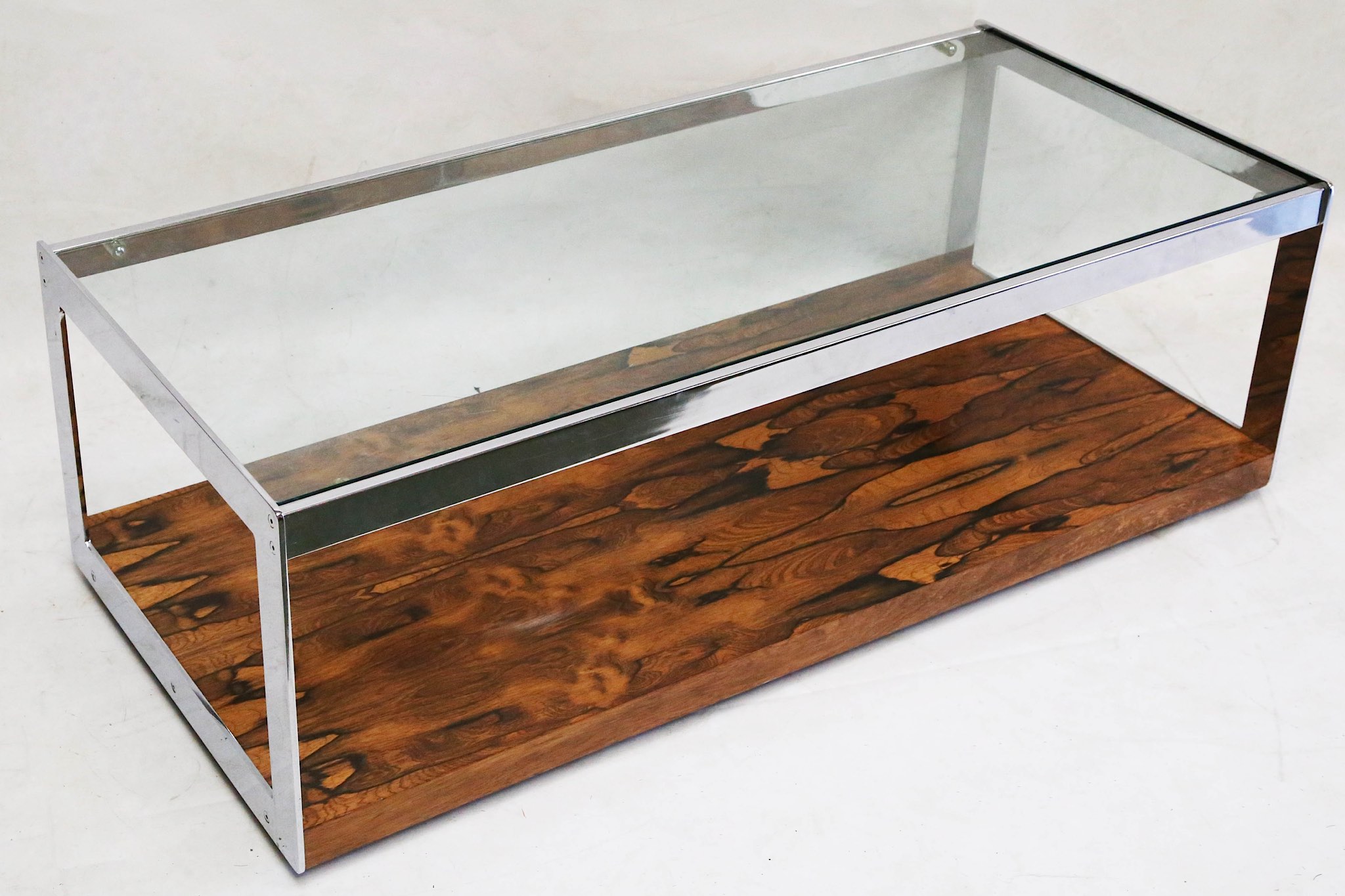 A 1970s Merrow Associates coffee table, glass top with rosewood base and chrome supports, (121 x