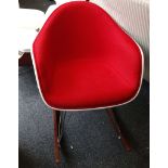 A Charles Eames style white shell chair with red upholstery on rocker base