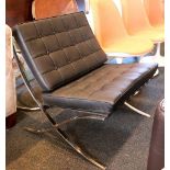 A Marcel Breuer style Barcelona chair and footstool, black leather on steel frame.