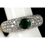 An emerald set ring with diamond set shoulders