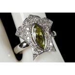 A tear shaped peridot ring with diamond cluster border