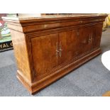 A Charles X style, marble topped side cabinet with three cushion frieze drawers over four cupboard