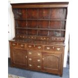 An antique oak dresser with plate/shelves and spice drawers over a base with three frieze drawers