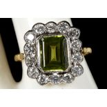 A square cut peridot ring, with diamond borders, on yellow gold shank