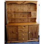 A pine kitchen dresser with plate shelves and spice cupboards on a base with four drawers flanked by