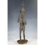 A large African bronze standing figure of a warrior wearing a mask decoration, supplied on drum