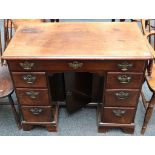 A George III mahogany kneehole desk, with arrangement of drawers around cupboard, raised on