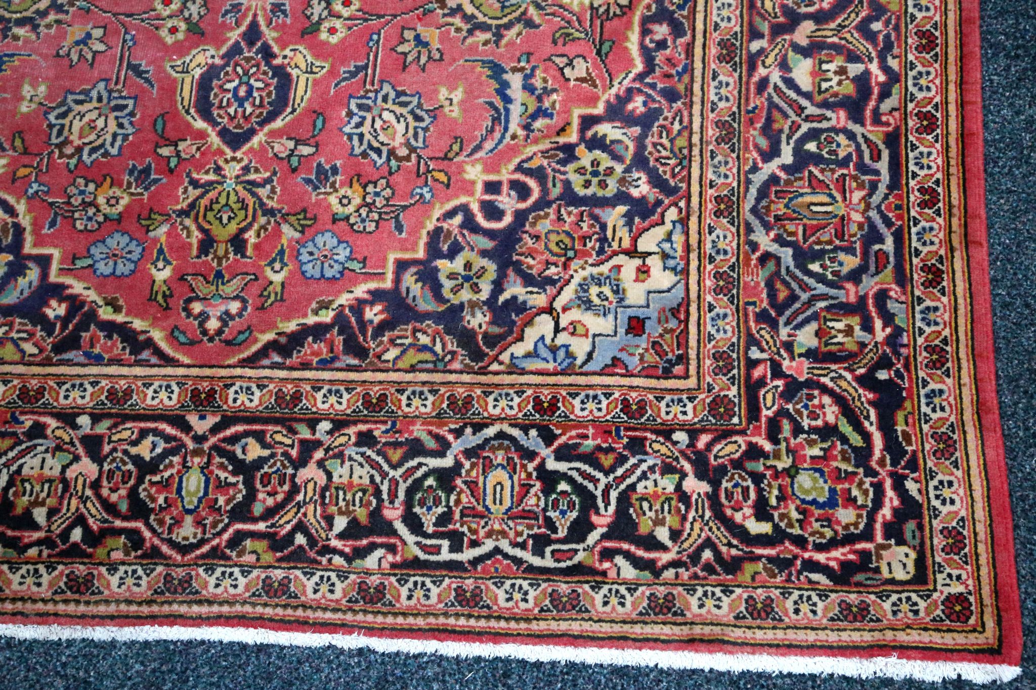 An antique Persian kashan with central blue medallion on cherry field