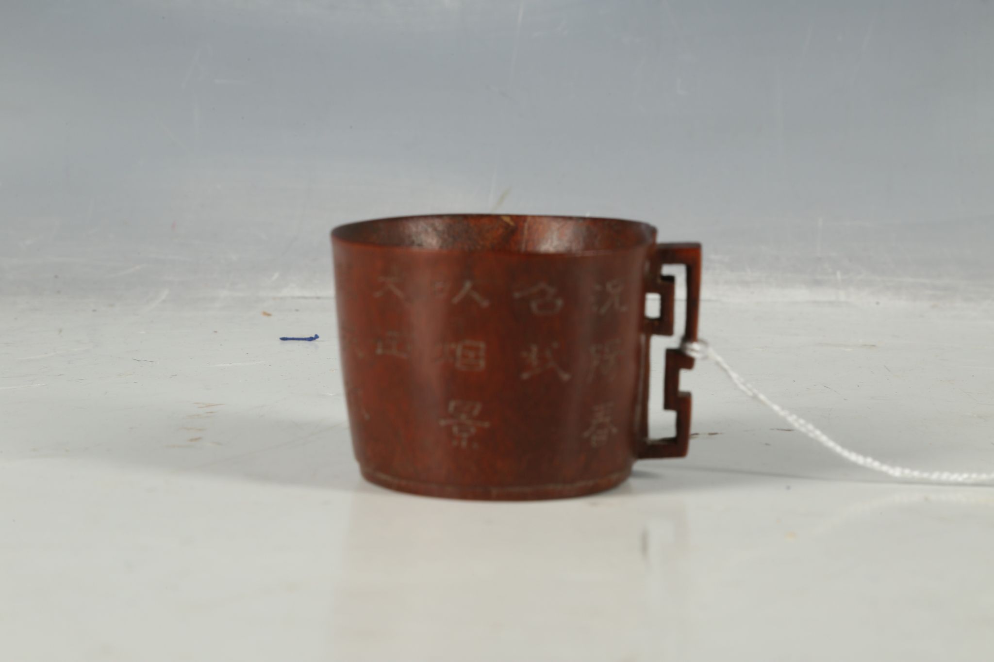 A Chinese bamboo carved cup with a decorative carved handle and calligraphic inscriptions around the