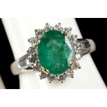 An 18ct white gold, emerald and diamond cluster ri
