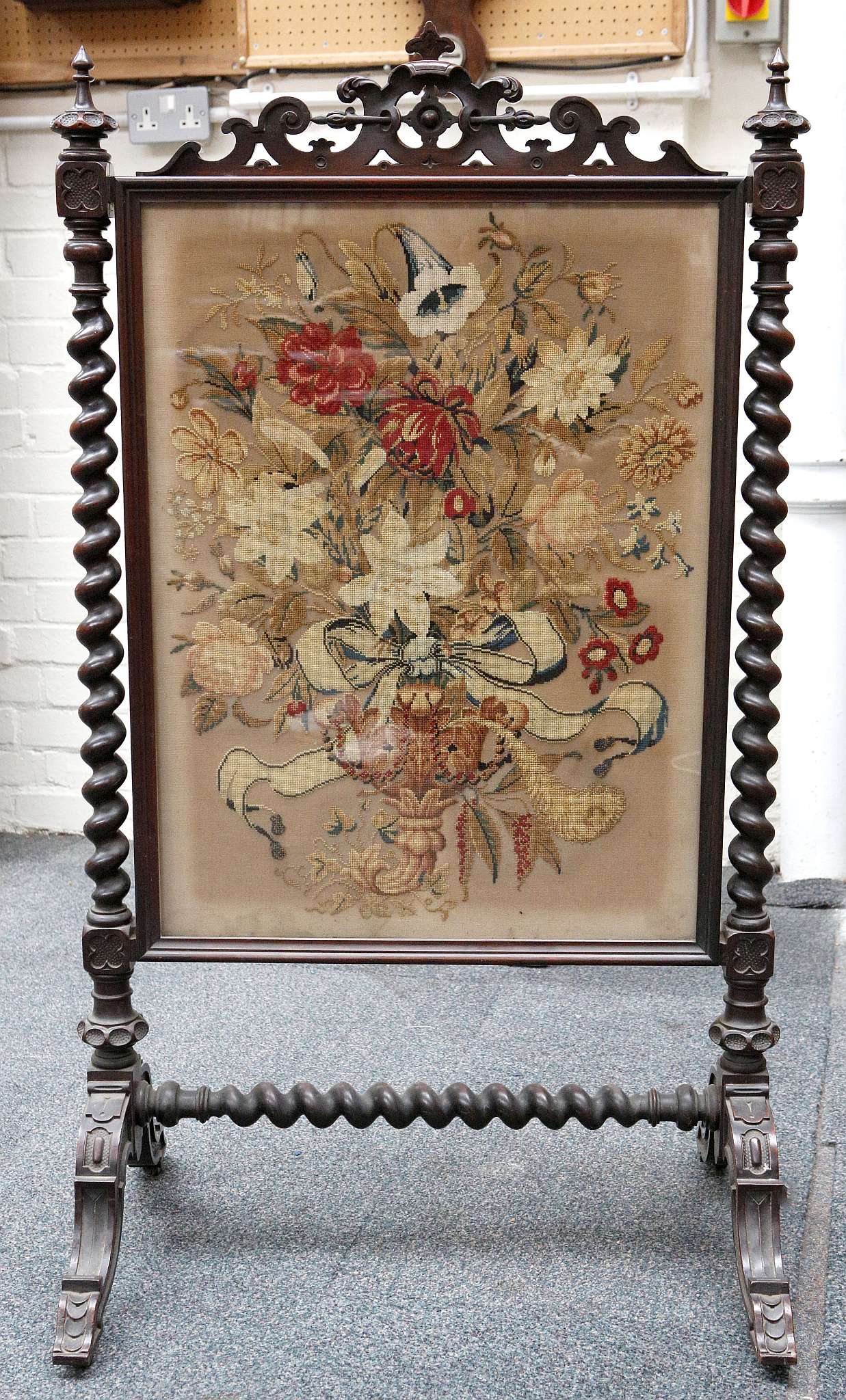 A Victorian mahogany free standing fire screen with floral tapestry panel, pierced and carved top,