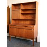 A 1960s teak sideboard wall unit, with shelves and drop down cupboard over cupboards, raised on