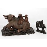 Two wooden carvings of buffalo, each carrying boys on their backs, 23 x 15cm high