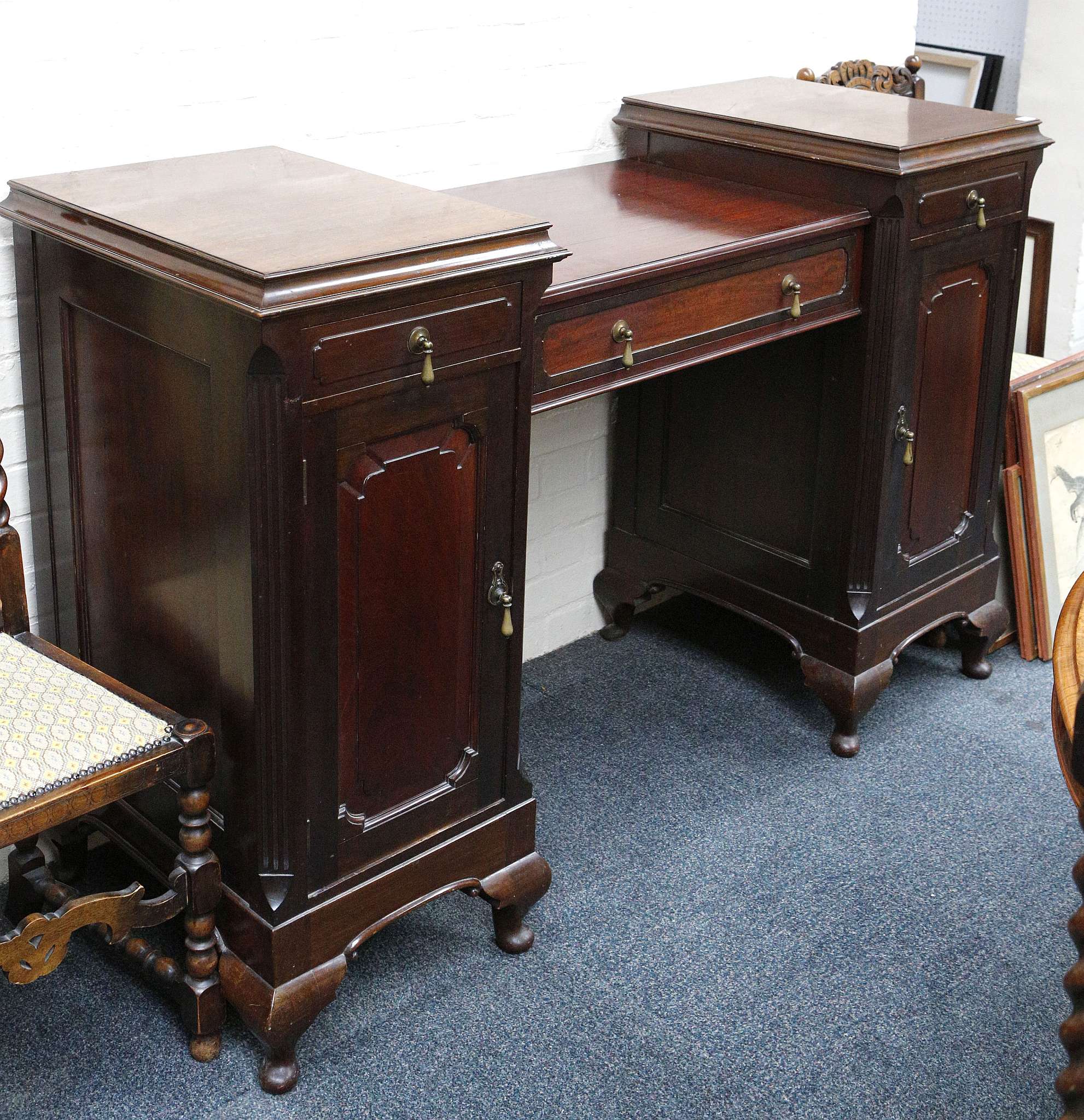 An Edwardian mahogany sideboard with central drawer over an open recess flanked by two pedestals,