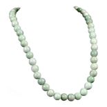 A CHINESE JADEITE NECKLACE. Comprising fifty circular beads strung with a yellow metal clasp, 58cm