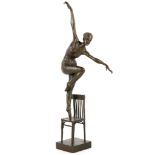 A bronzed sculpture of a ballet dancer atop of a c