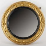 A late 19th century giltwood framed circular convex mirror, with baubles in the round and reeded,