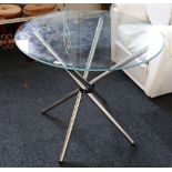 A post-modernist circular glass-top table raised on polished tubular metal legs