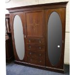 An Edwardian 3 door inlaid mahogany wardrobe with 3 mirrored doors, having centre ½ door over 4