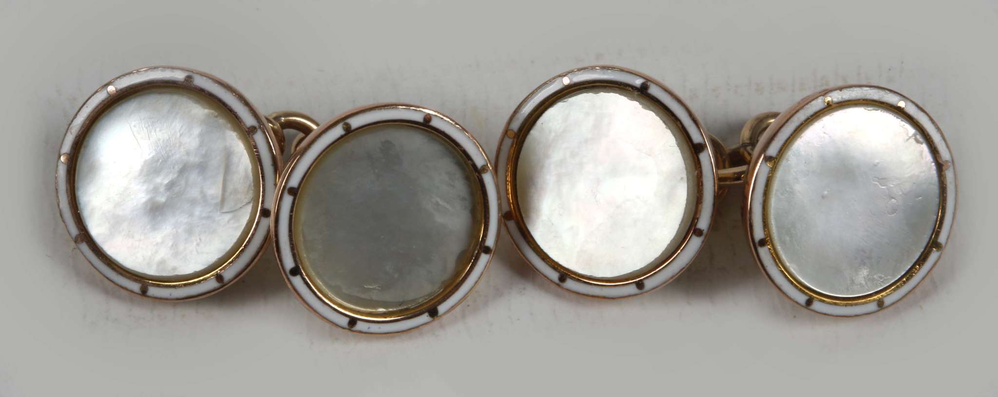 A pair of white enamel and mother of pearl 9ct gold cuff links