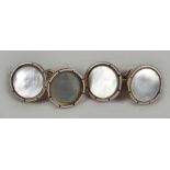 A pair of white enamel and mother of pearl 9ct gold cuff links