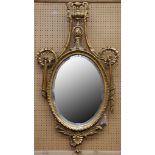 A Georgian style neoclassical giltwood framed oval mirror with beveled edge, the frame with a vase