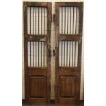 A pair of wooden doors with iron jail bars and lat
