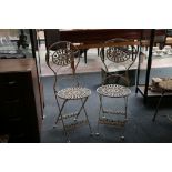 A cream painted metal bistro table and two chairs