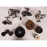 A collection of seven vintage fishing reels comprising a 5" diameter black anodised aluminium ally
