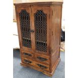 An Indian hardwood cabinet with iron grill decorated doors, over four short drawers, raised on a
