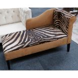 A modern day bed, upholstered in tan and faux zebra striped material, raised on square section legs