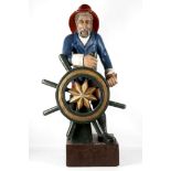A wooden carved and painted sea Captain at the helm ship's wheel, 93cm