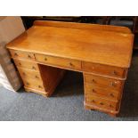 A late Victoran desk, stained pine finish, 9 drawers, brass Gothic handles, 121cm wide