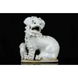 A CHINESE WHITE GLAZED BUDDHIST LION DOG AND PUP. Qing. Raised on a low rectangular base, the
