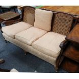 An Edwardian three piece mahogany framed Bergere suite, with caned back and sides and upholstered in