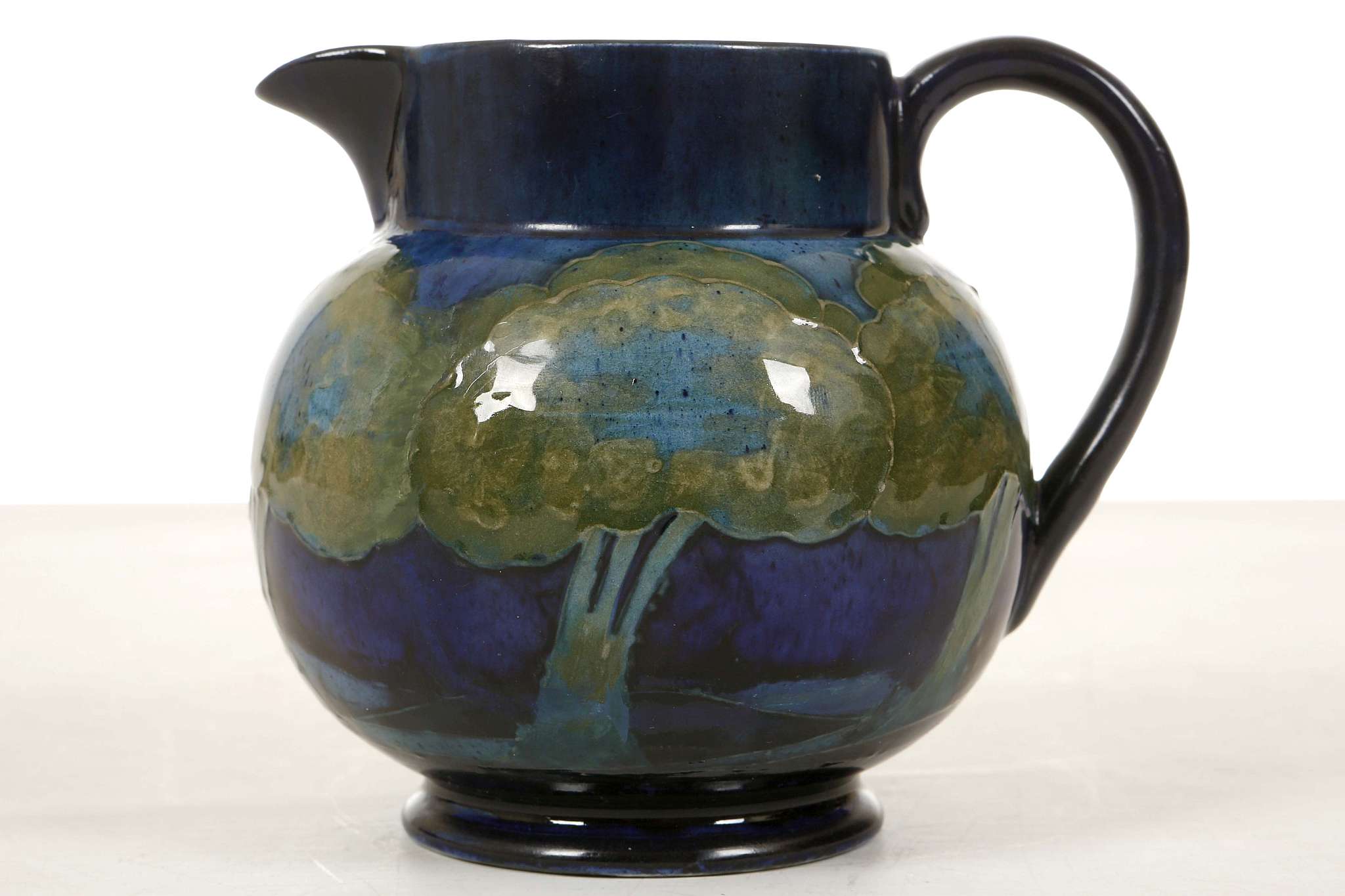 A WILLIAM MOORCROFT 'MOONLIT BLUE' JUG, circa 1925, the body painted with a continuous frieze of