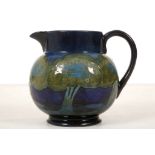 A WILLIAM MOORCROFT 'MOONLIT BLUE' JUG, circa 1925, the body painted with a continuous frieze of