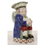 A FINE YORKSHIRE TOBY JUG, circa 1810, with a warty face, modelled seated with a jug resting on