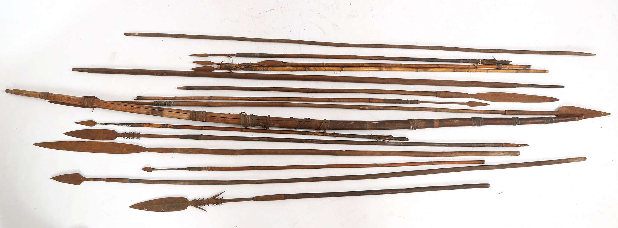 A tribal bow, split wood with grass banding, arrows, throwing spears with feather blade and barb